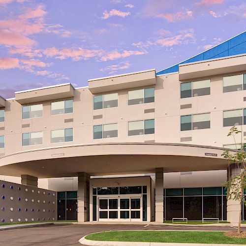 The image shows the exterior of a modern hotel building with a blue accent wall and the logo 